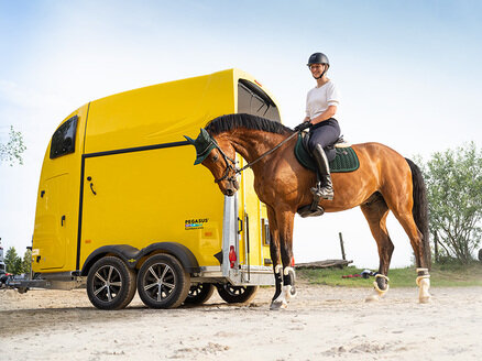 Cavalière assise sur son cheval devant un van jaune Humbaur Pegasus Style | © Humbaur GmbH