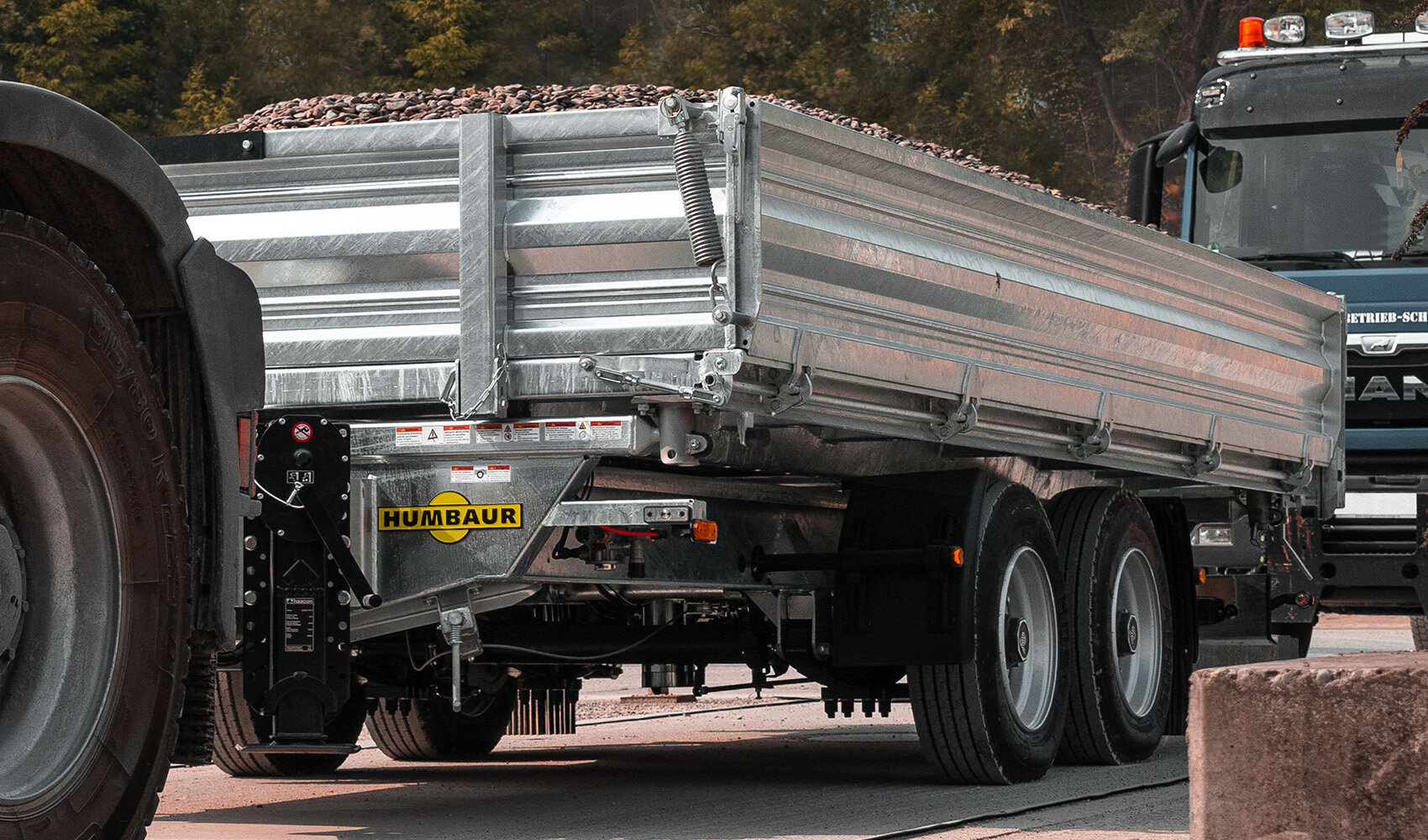 Humbaur lorry trailer loaded with stones is pulled along a road by a towing vehicle.  | © Humbaur GmbH